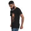 Un homme porte le T-shirt Soleil floral bohème, un modèle noir à col V mettant en avant un design artistique et élégant. Le motif représente un soleil rayonnant entouré de fleurs délicates et de lianes entrelacées, créant une esthétique à la fois naturelle et raffinée. Ce t-shirt unisexe allie confort et style, parfait pour un look bohème chic et intemporel.