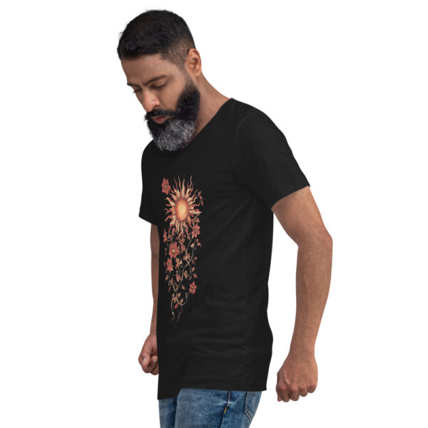 Un homme porte le T-shirt Soleil floral bohème, un modèle noir à col V mettant en avant un design artistique et élégant. Le motif représente un soleil rayonnant entouré de fleurs délicates et de lianes entrelacées, créant une esthétique à la fois naturelle et raffinée. Ce t-shirt unisexe allie confort et style, parfait pour un look bohème chic et intemporel.